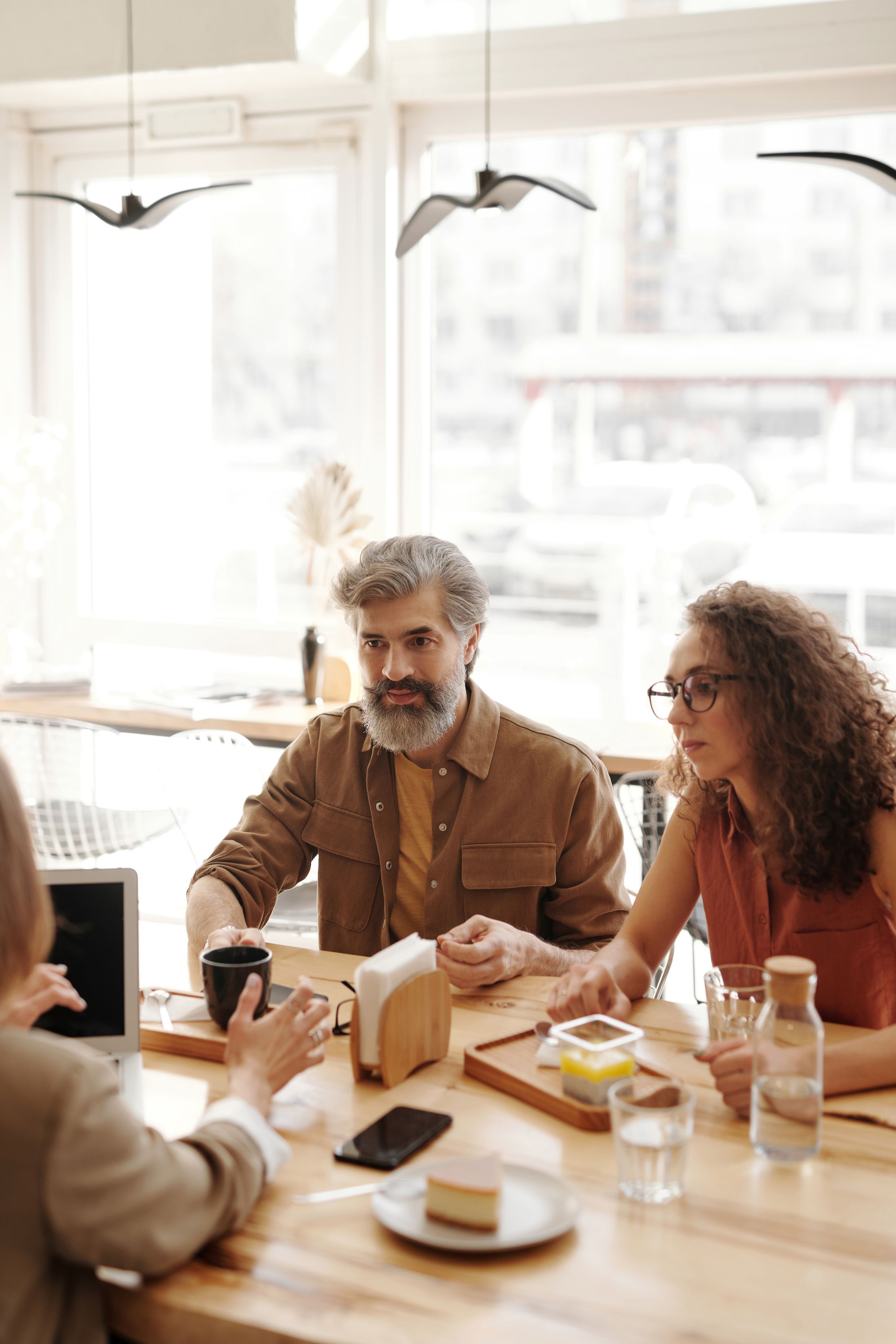 Drie mensen in gesprek aan een tafel met koffie